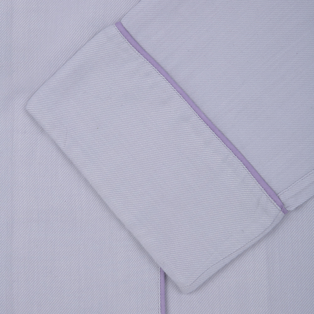 The Ladies' Lilac Cotton-Cashmere Pyjama Set by Turnbull & Asser, with purple piping, collared button-up top featuring a chest pocket, and matching drawstring bottoms, is folded and displayed on a white background.