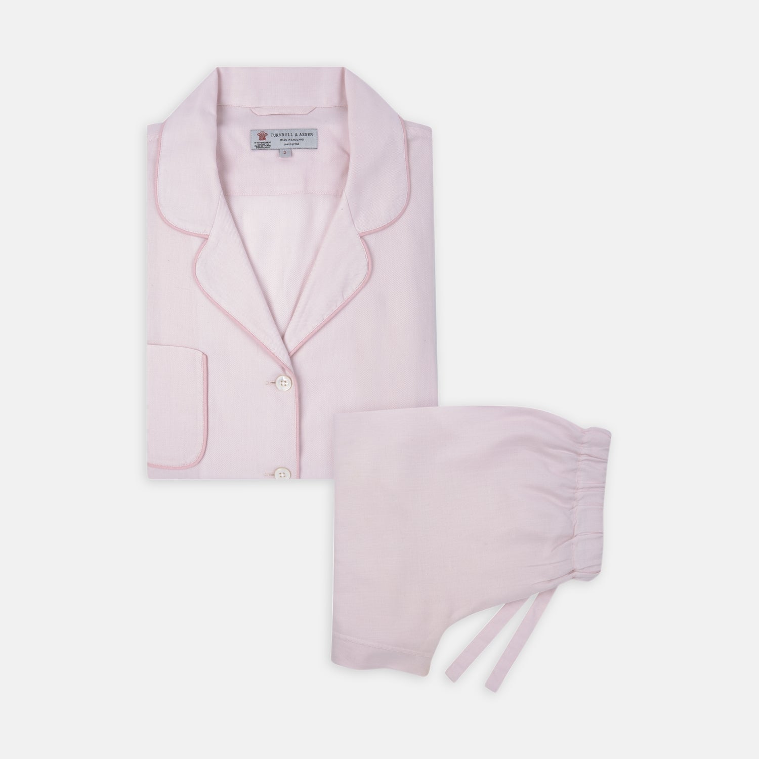 View 1 of product The Turnbull & Asser Ladies' Pink Cotton-Cashmere Pyjama Set features a collared, button-up top with a pocket and matching drawstring pants, both detailed with subtle piping, displayed on a plain white background.