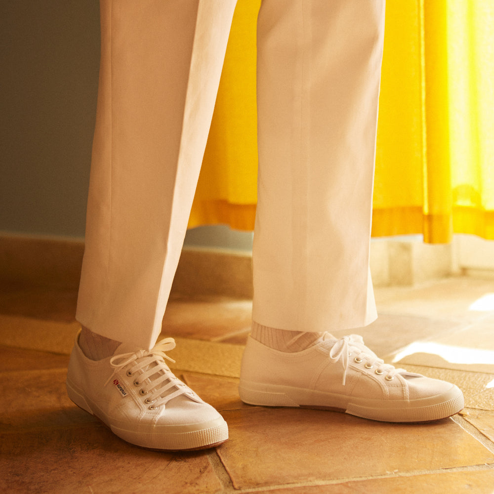 Turnbull & Asser’s White Cotton Pleated Trousers, a summer classic, are elegantly displayed against a crisp white backdrop.