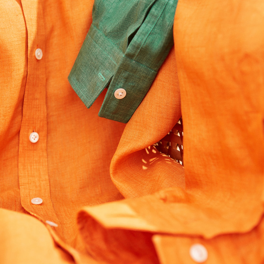 The Turnbull & Asser Orange Weekend Fit Long Sleeve Linen Shirt features a Derby collar, 1-button cuffs, white buttons, and a relaxed fit, shown against a white background.