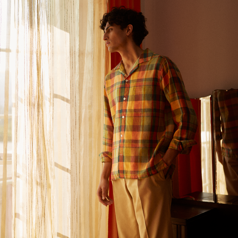 Turnbull & Asser's Orange Madras Check Holiday Fit Long Sleeve Linen Shirt features a bold plaid in orange, yellow, green, and blue with a revere collar and 1-button cuff—ideal for effortless holiday style. Laid flat on white background.