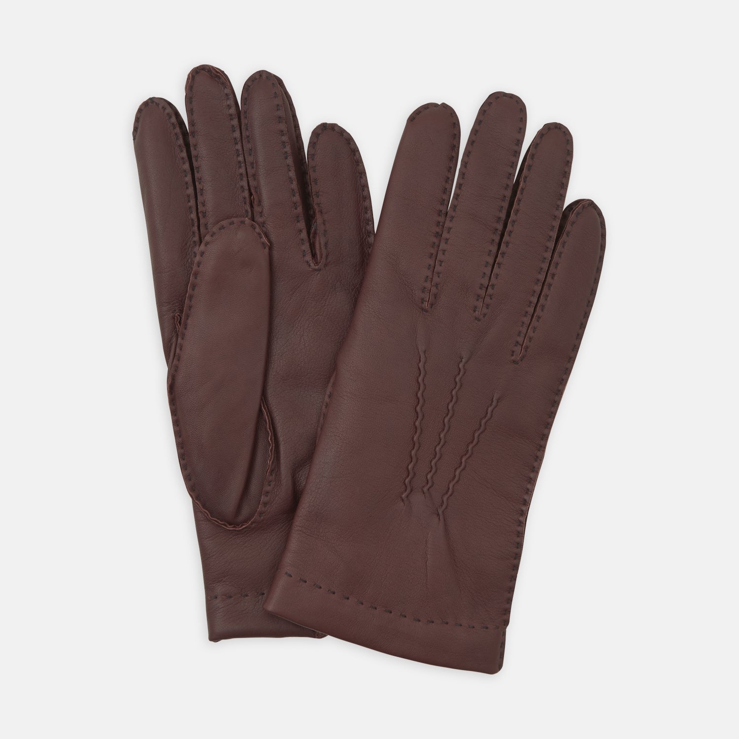 View 1 of product Turnbull & Asser’s Brown Hairsheep Leather Gloves, featuring visible stitching and decorative raised seams on the back, are displayed overlapping each other against a white background.