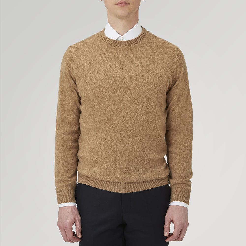 A folded Natural Crew Neck Cashmere Jumper by Turnbull & Asser, in light brown, features a visible brand label and one sleeve neatly laid across the front of this smart casual luxury Scottish sweater.