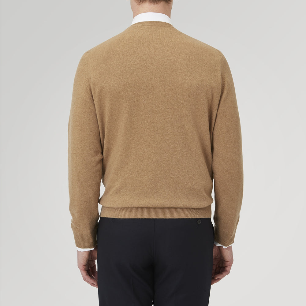 A folded Natural Crew Neck Cashmere Jumper by Turnbull & Asser, in light brown, features a visible brand label and one sleeve neatly laid across the front of this smart casual luxury Scottish sweater.