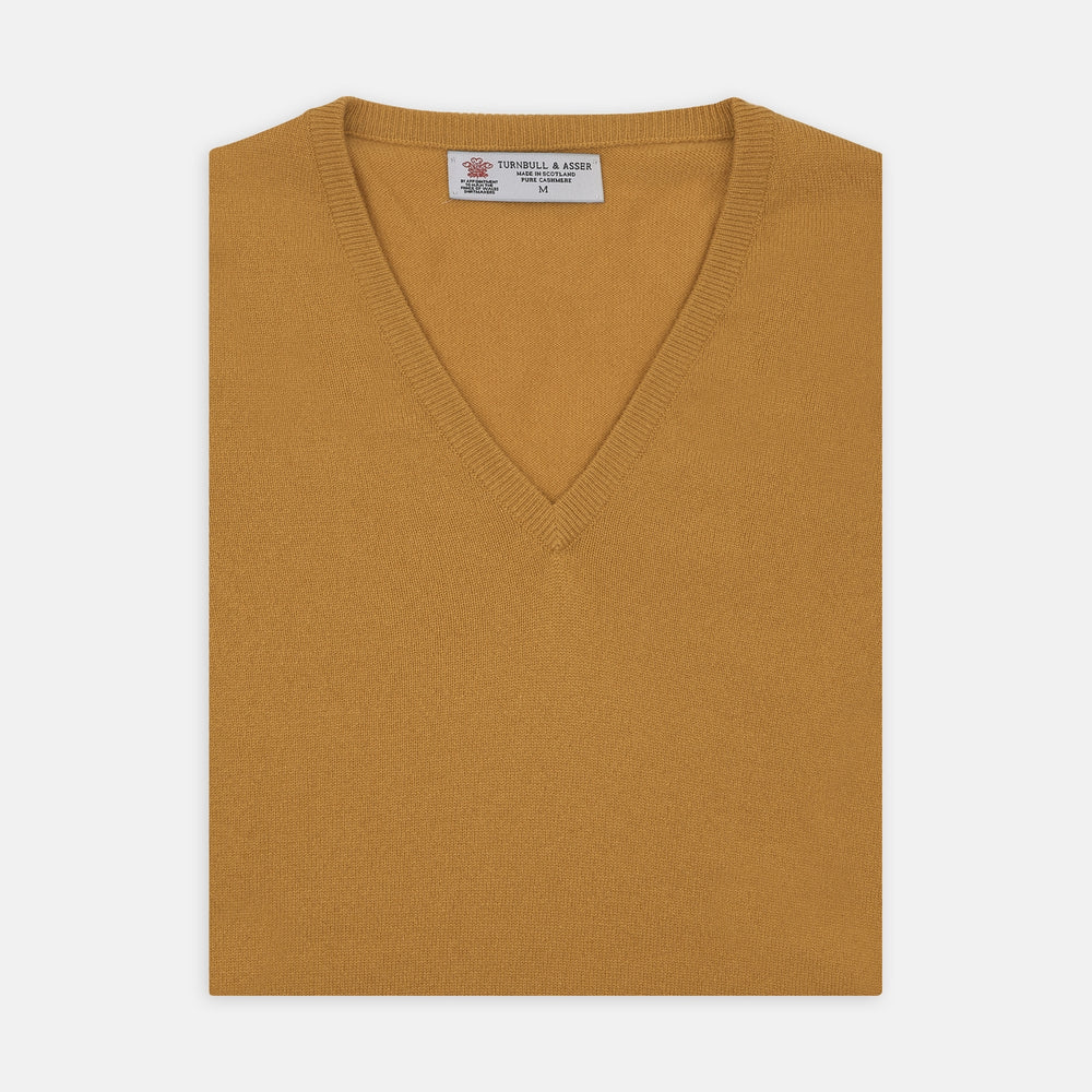 The Sunflower Yellow V-Neck Cashmere Slipover by Turnbull & Asser is neatly folded on a white background, showing the front and label—ideal for formal layering or as a versatile cashmere addition to your wardrobe.
