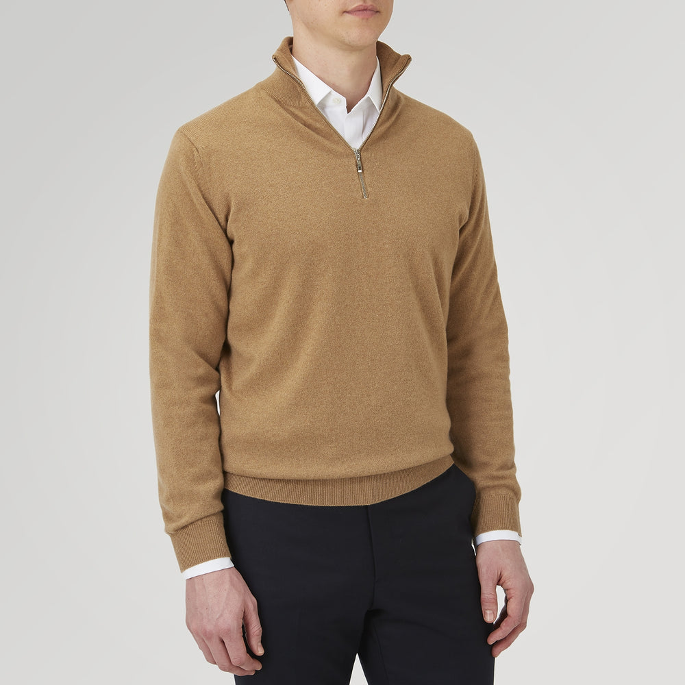 The Turnbull & Asser Natural Half-Zip Cashmere Jumper, light brown with a high collar and silver zip, is folded neatly against a white background. One sleeve shows its ribbed cuff—ideal for stylish layering.