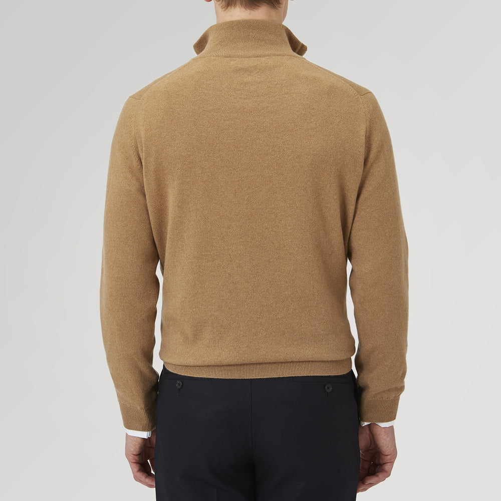 The Turnbull & Asser Natural Half-Zip Cashmere Jumper, light brown with a high collar and silver zip, is folded neatly against a white background. One sleeve shows its ribbed cuff—ideal for stylish layering.