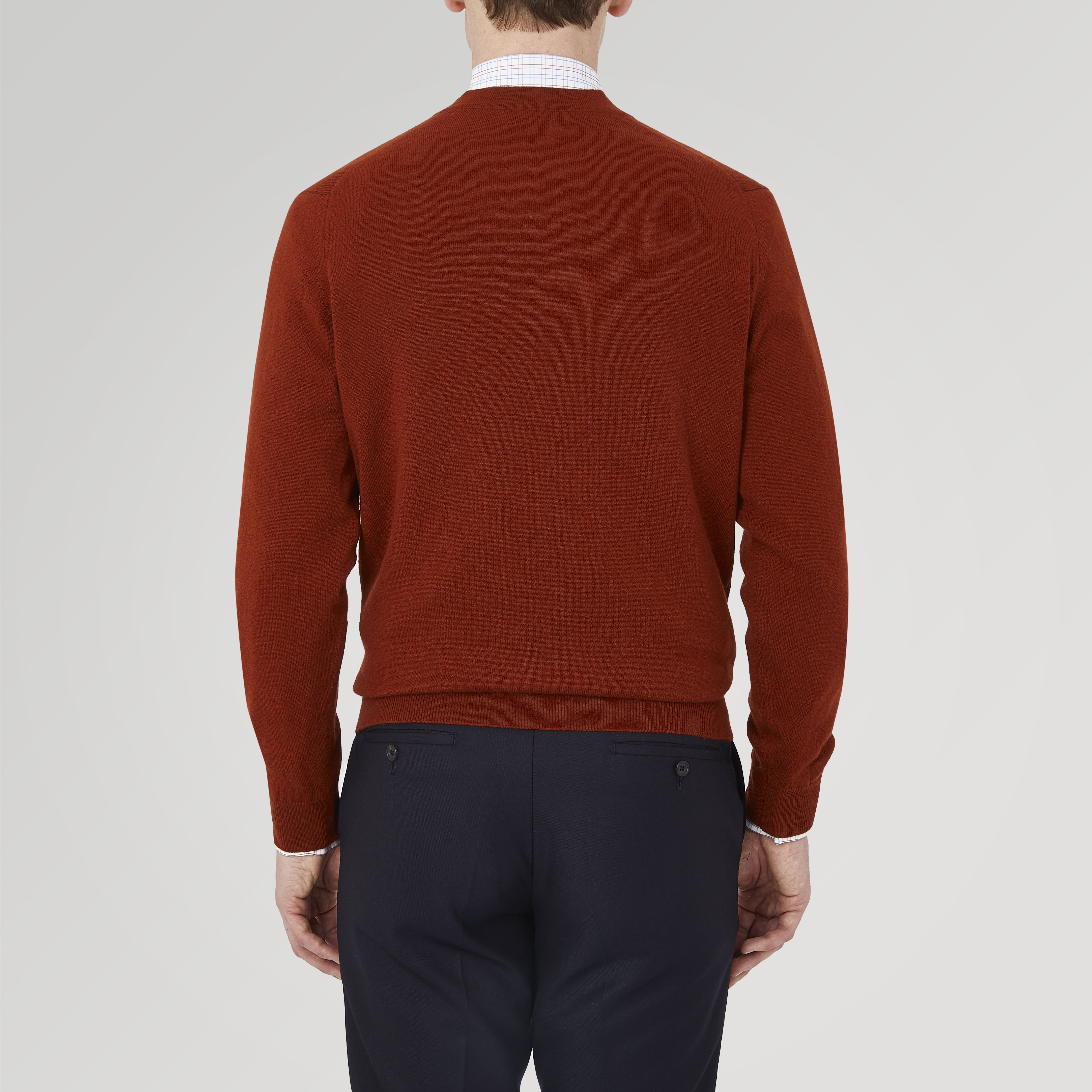 View 3 of product The Harissa Cashmere Cardigan by Turnbull & Asser, in deep red-brown 21GG knit, is folded to display its V-neck, ribbed cuffs, and two buttons against a white background.