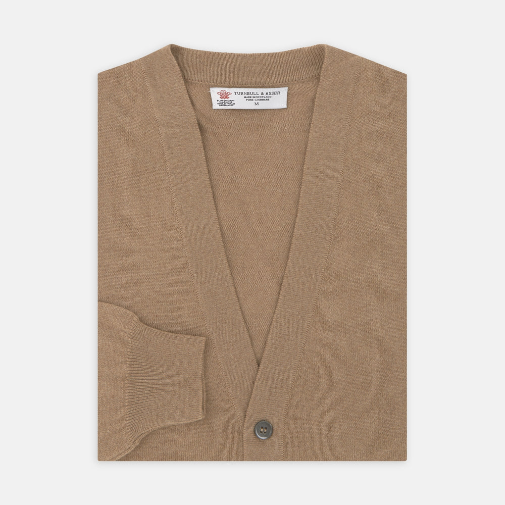 A Natural Cashmere Cardigan by Turnbull & Asser, light brown with a V-neckline, ribbed cuffs, and button closure, is neatly folded and displayed against a white background.
