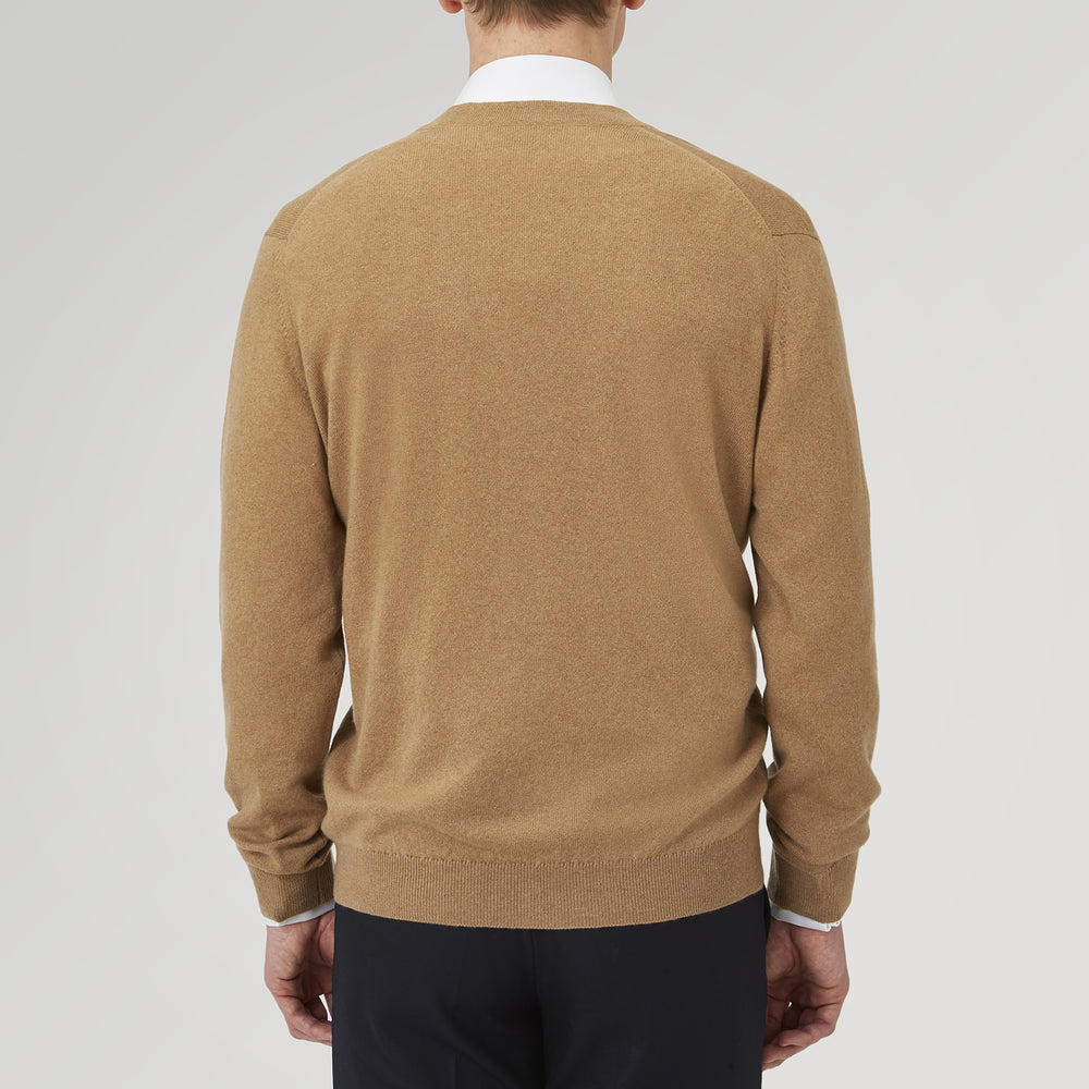 A Natural Cashmere Cardigan by Turnbull & Asser, light brown with a V-neckline, ribbed cuffs, and button closure, is neatly folded and displayed against a white background.