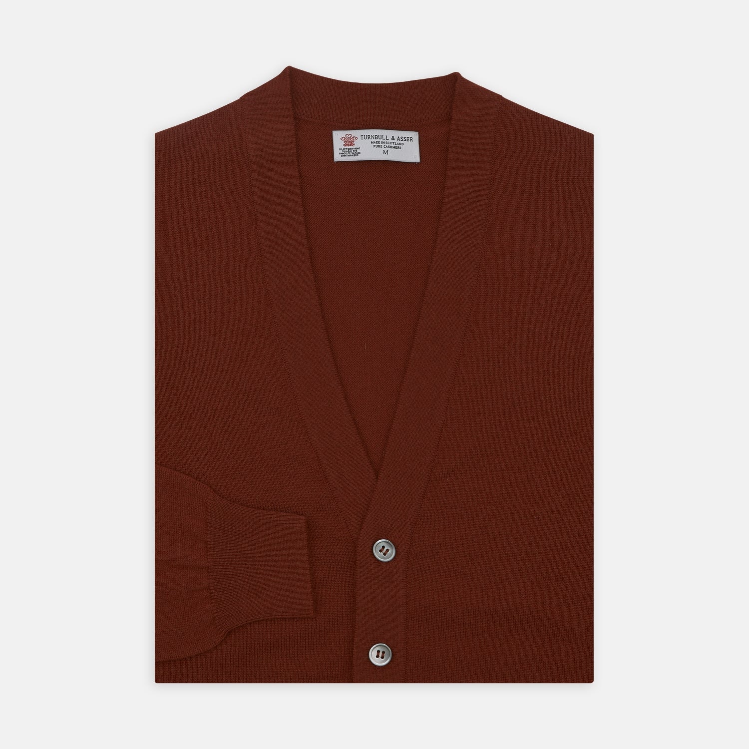 View 1 of product The Harissa Cashmere Cardigan by Turnbull & Asser, in deep red-brown 21GG knit, is folded to display its V-neck, ribbed cuffs, and two buttons against a white background.