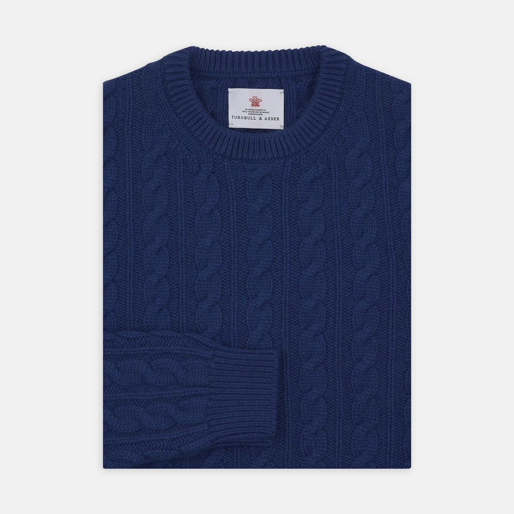 The Blue Crew Neck Cable Knit Cashmere Jumper by Turnbull & Asser features a chunky cable knit, ribbed crew neck and cuffs, and a visible label inside the collar.