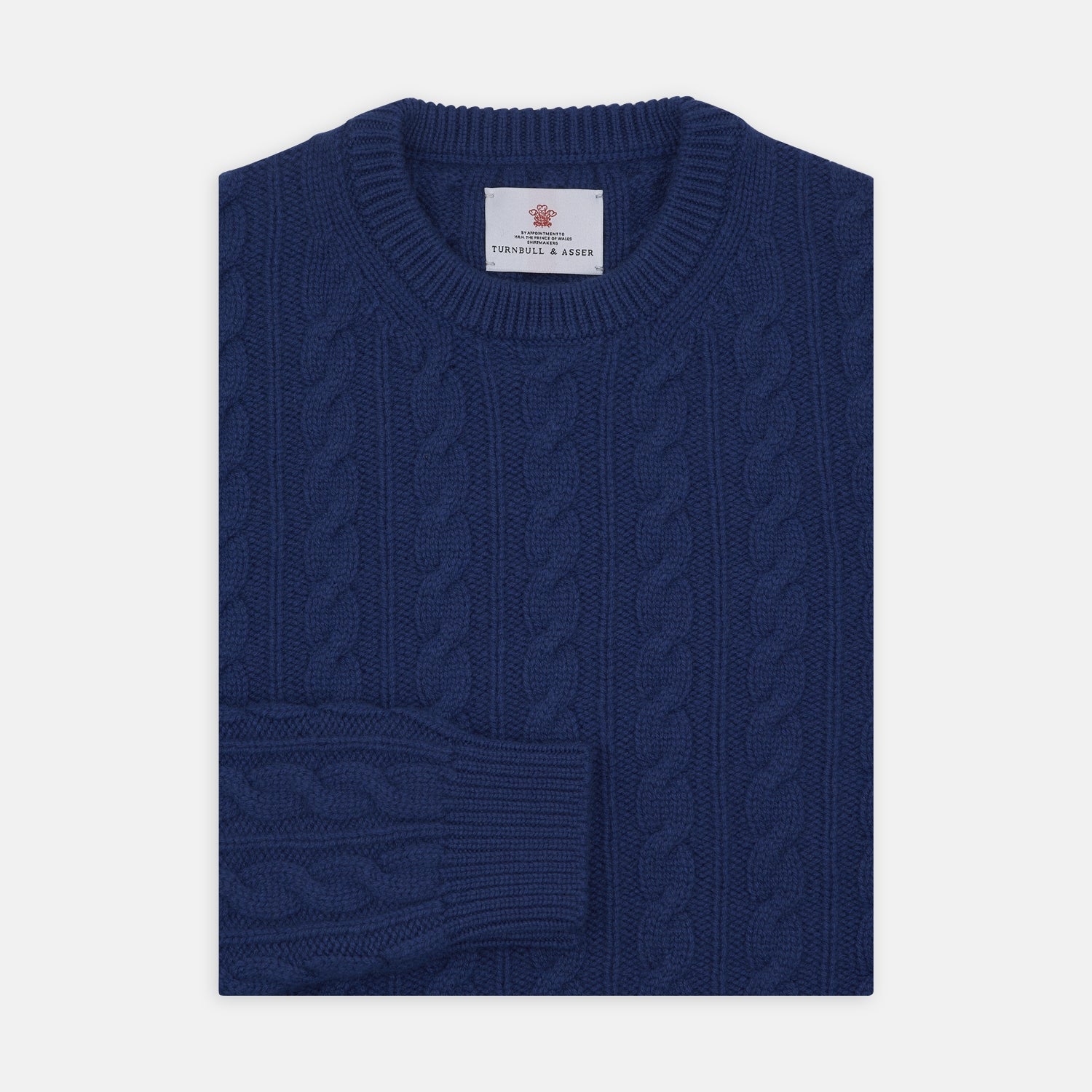 View 1 of product The Blue Crew Neck Cable Knit Cashmere Jumper by Turnbull & Asser features a chunky cable knit, ribbed crew neck and cuffs, and a visible label inside the collar.