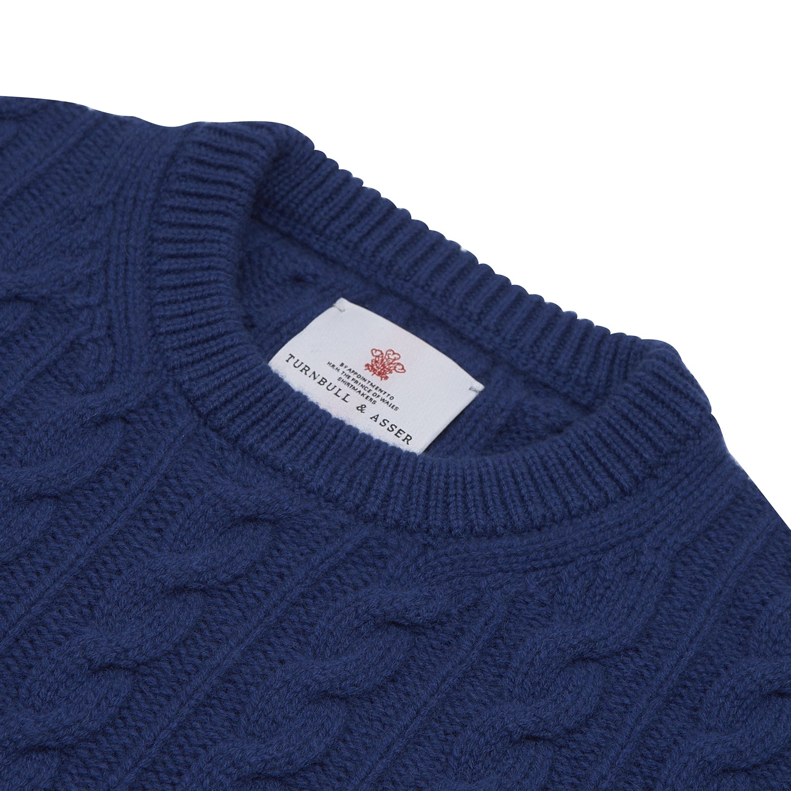 View 4 of product The Blue Crew Neck Cable Knit Cashmere Jumper by Turnbull & Asser features a chunky cable knit, ribbed crew neck and cuffs, and a visible label inside the collar.