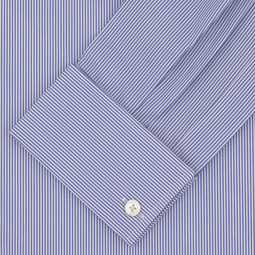 The Turnbull & Asser Tailored Fit Blue Fine Bengal Stripe Cotton Shirt features a Kent collar, double cuffs, and thin white stripes. Displayed neatly folded against a white background.