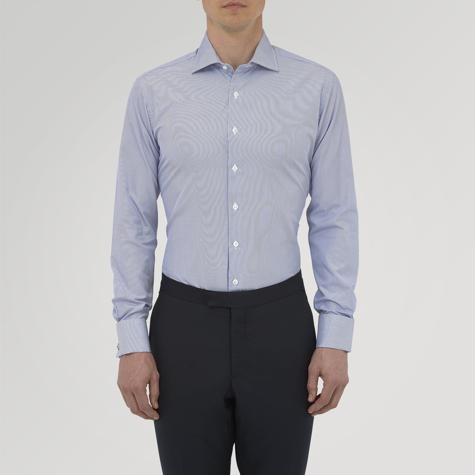 View 2 of product The Turnbull & Asser Tailored Fit Blue Fine Bengal Stripe Cotton Shirt features a Kent collar, double cuffs, and thin white stripes. Displayed neatly folded against a white background.