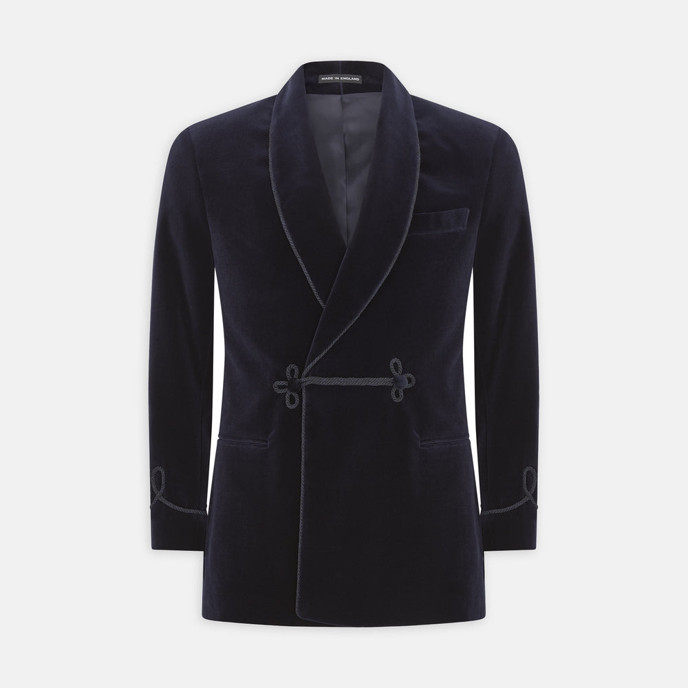 The Turnbull & Asser Navy Double Breasted Velvet Smoking Jacket features a shawl collar, corded closures on the front and cuffs, and a chest pocket, shown against a light gray background.