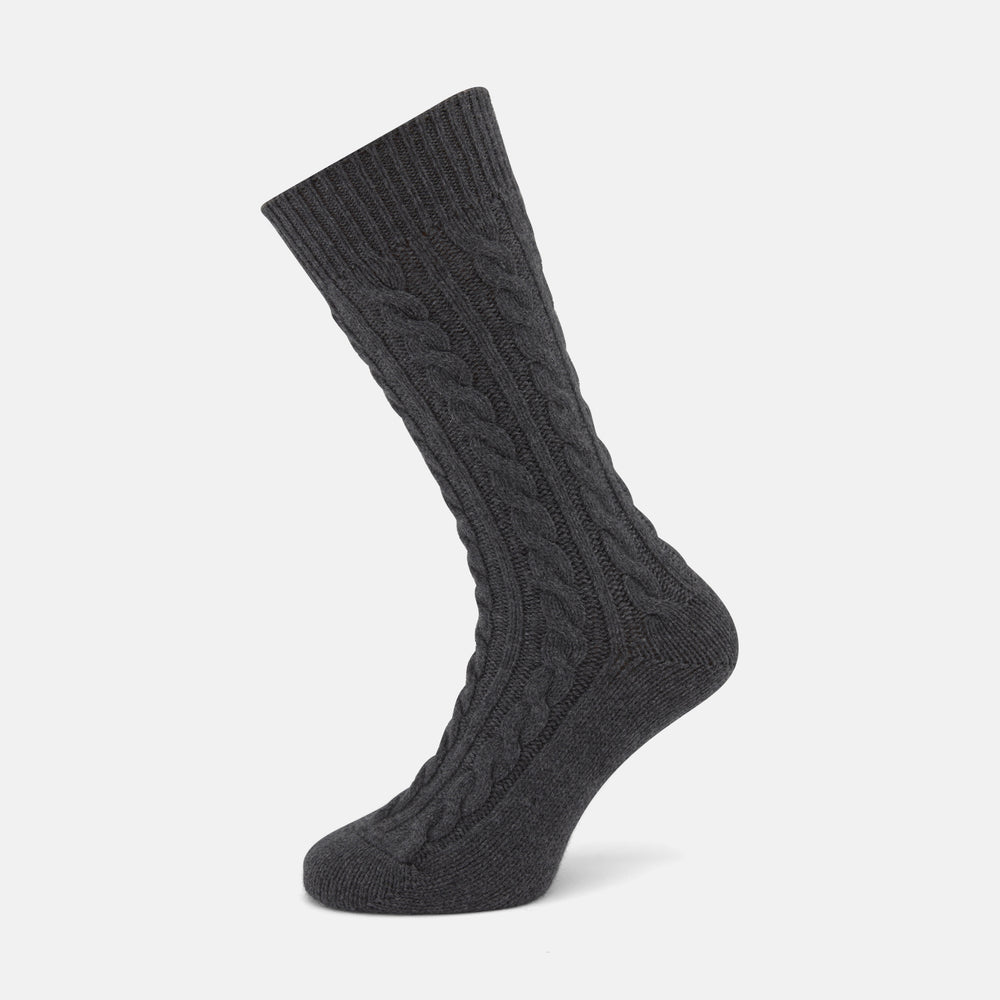 The Dark Grey Cashmere Cable-Knit Sock by Turnbull & Asser stands upright against a white background, featuring a mid-calf length, ribbed cuff, and thick cable-knit design for a luxurious, premium feel.