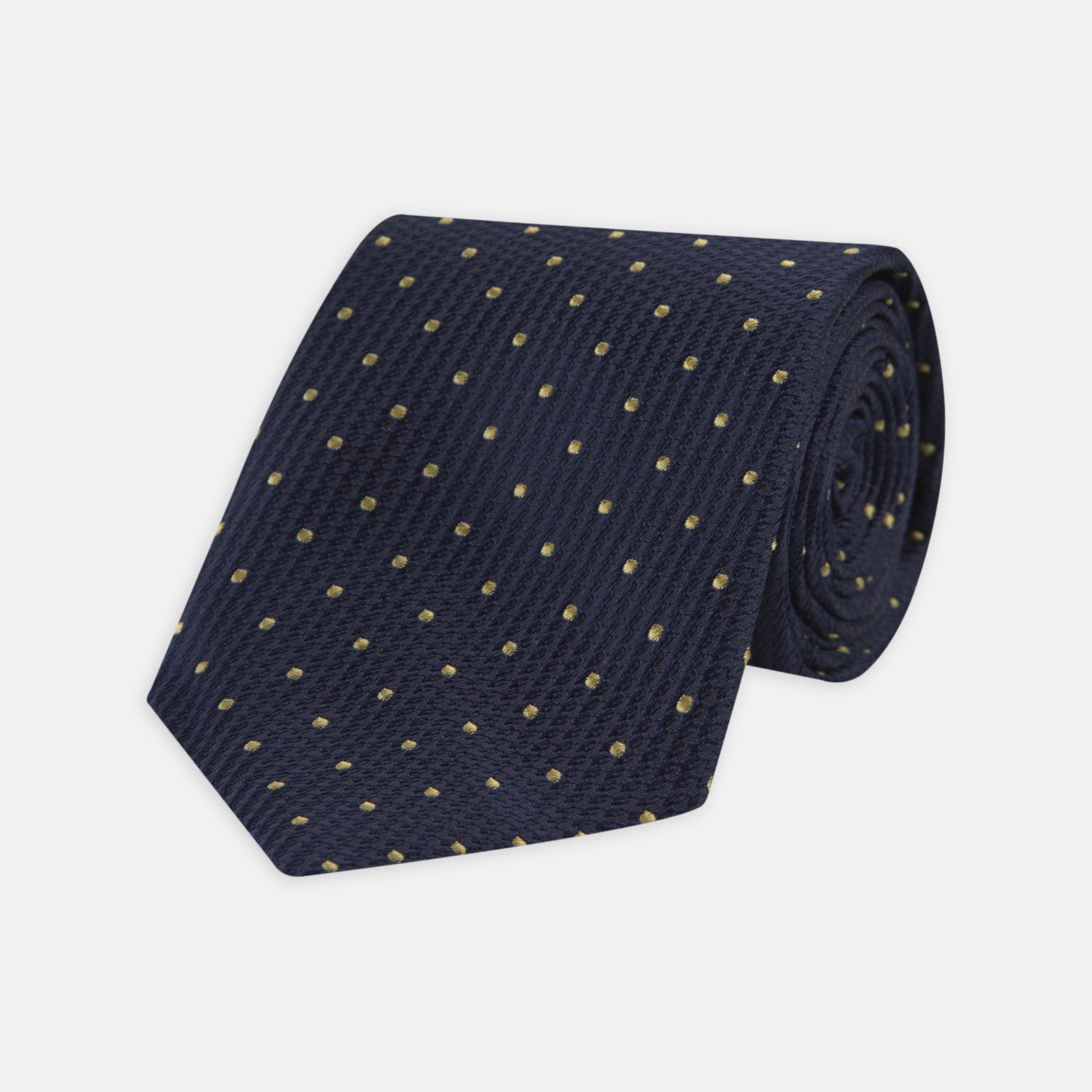 View 1 of product The Turnbull & Asser Navy and Gold Spot Lace Silk Tie, ideal for office wear, is shown rolled up on a white background.