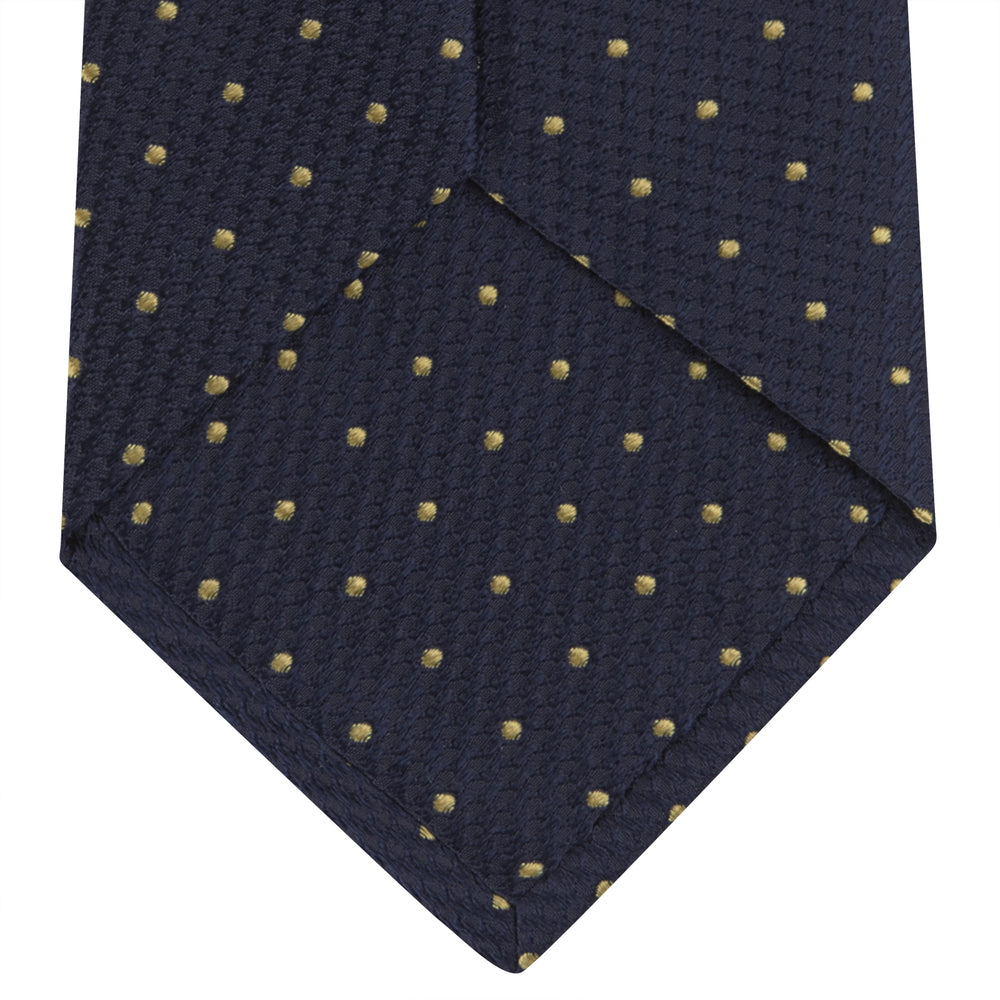The Turnbull & Asser Navy and Gold Spot Lace Silk Tie, ideal for office wear, is shown rolled up on a white background.