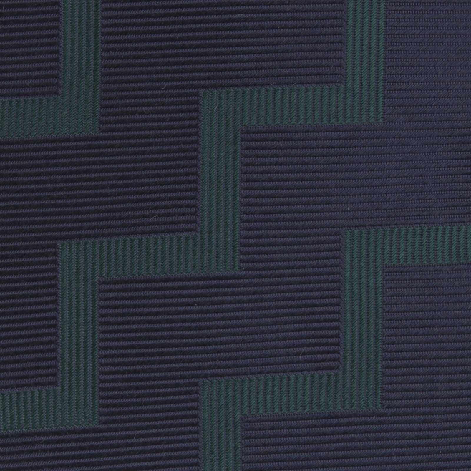 View 3 of product A modern essential, the Turnbull & Asser Navy and Forest Green Striped Zigzag Silk Tie features a bold navy and forest green zigzag pattern, elegantly displayed rolled on a crisp white background.