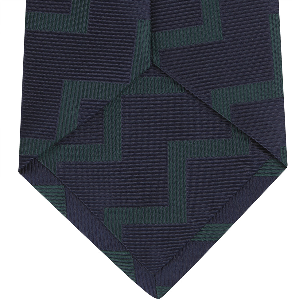 A modern essential, the Turnbull & Asser Navy and Forest Green Striped Zigzag Silk Tie features a bold navy and forest green zigzag pattern, elegantly displayed rolled on a crisp white background.