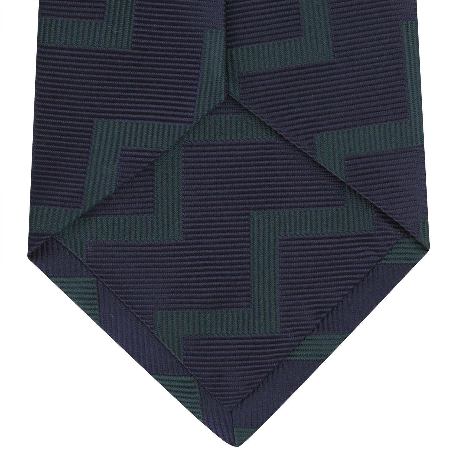 View 4 of product A modern essential, the Turnbull & Asser Navy and Forest Green Striped Zigzag Silk Tie features a bold navy and forest green zigzag pattern, elegantly displayed rolled on a crisp white background.