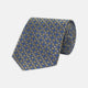 The Gold and Blue Circle and Spot Silk Tie by Turnbull & Asser features blue silk adorned with yellow and white circles and lines, rolled neatly on a light background—an elegant choice for complementing any office shirt.