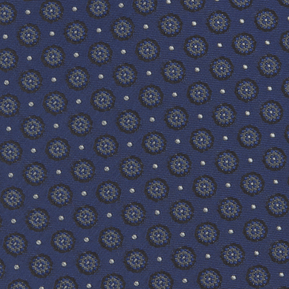 The Turnbull & Asser Navy Floral Spot Silk Tie, featuring a subtle light blue and gray pattern, is rolled up against a plain white background—an ideal accessory for any office shirt.