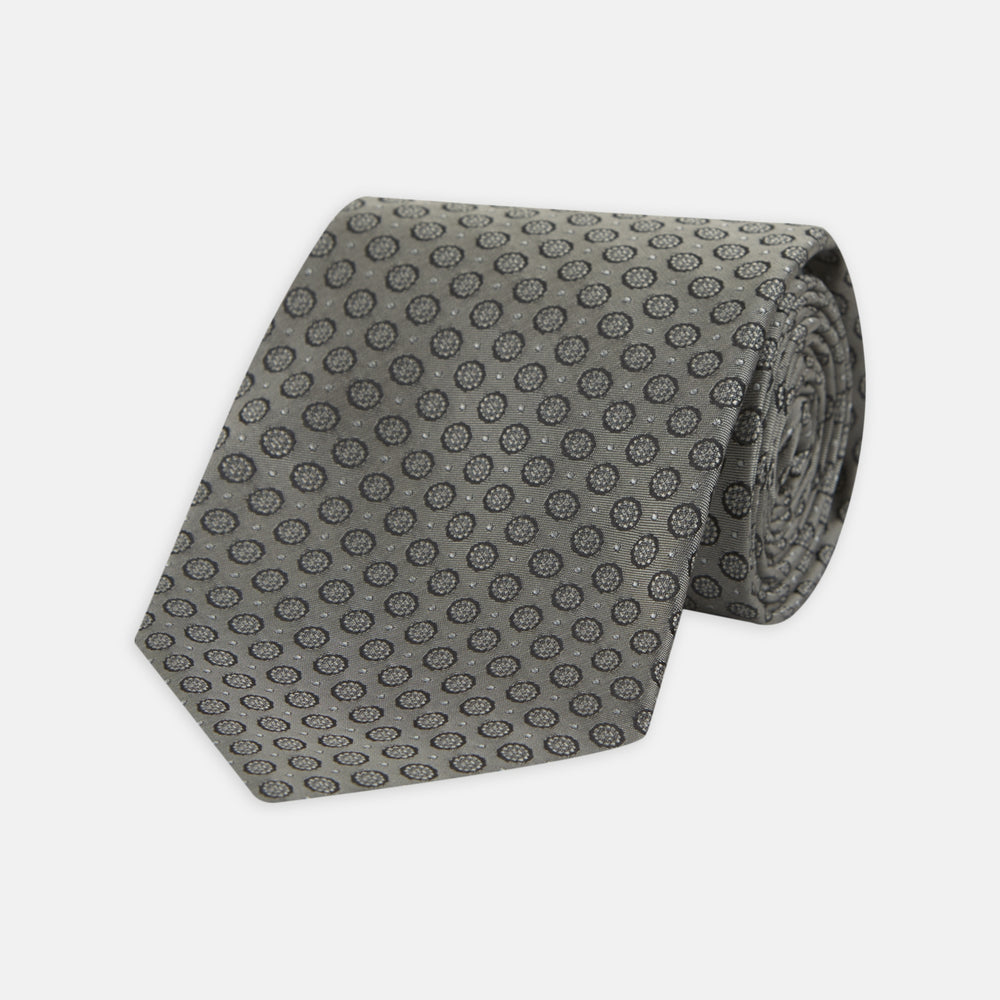 The Turnbull & Asser Grey Floral Spot Silk Tie, shown rolled up on a white background, features a classic black and white spot pattern.