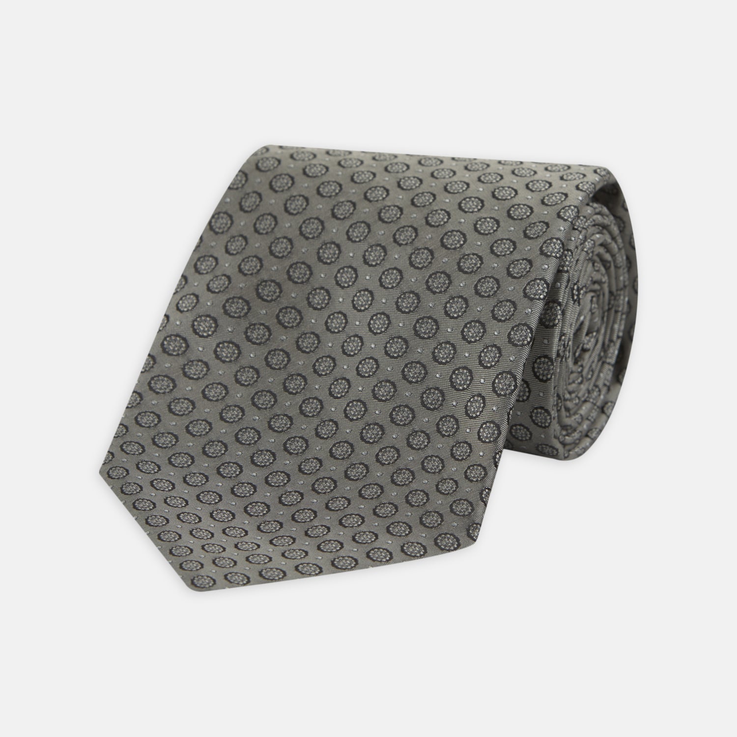 View 1 of product The Turnbull & Asser Grey Floral Spot Silk Tie, shown rolled up on a white background, features a classic black and white spot pattern.