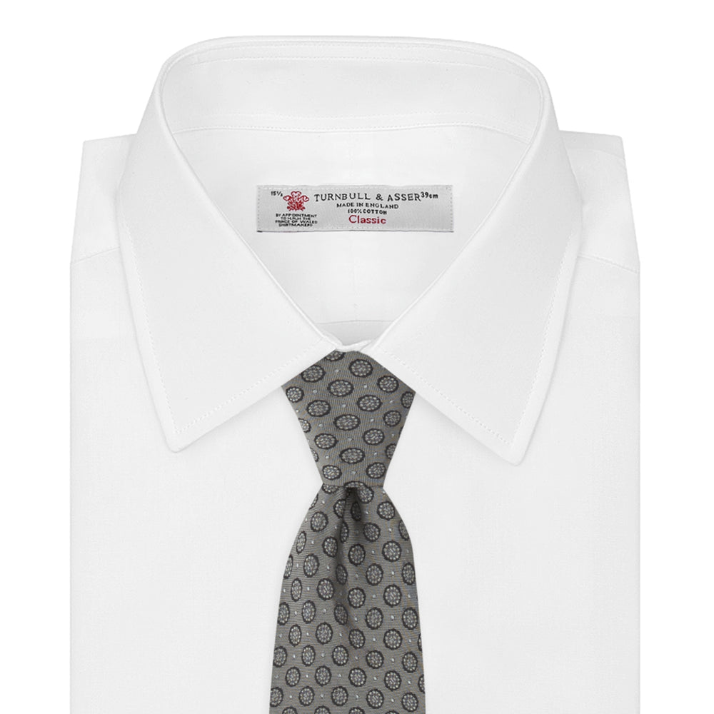 The Turnbull & Asser Grey Floral Spot Silk Tie, shown rolled up on a white background, features a classic black and white spot pattern.