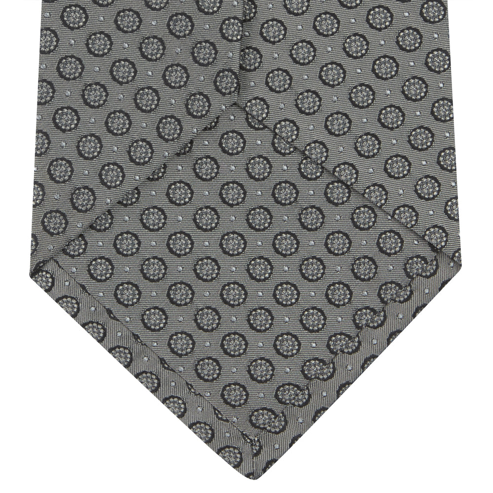 The Turnbull & Asser Grey Floral Spot Silk Tie, shown rolled up on a white background, features a classic black and white spot pattern.