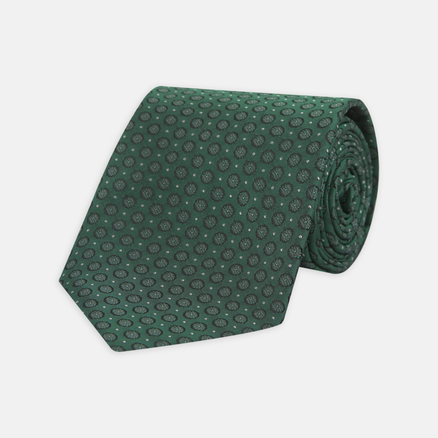 View 1 of product The Turnbull & Asser Green Floral Spot Silk Tie features small, light-colored circular dots on a classic green silk background—ideal for dressing up your favorite office shirt. Displayed rolled on a plain white backdrop.