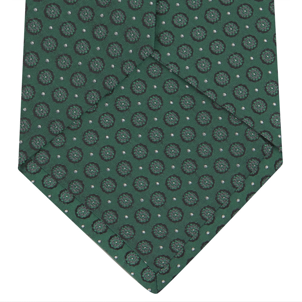 The Turnbull & Asser Green Floral Spot Silk Tie features small, light-colored circular dots on a classic green silk background—ideal for dressing up your favorite office shirt. Displayed rolled on a plain white backdrop.