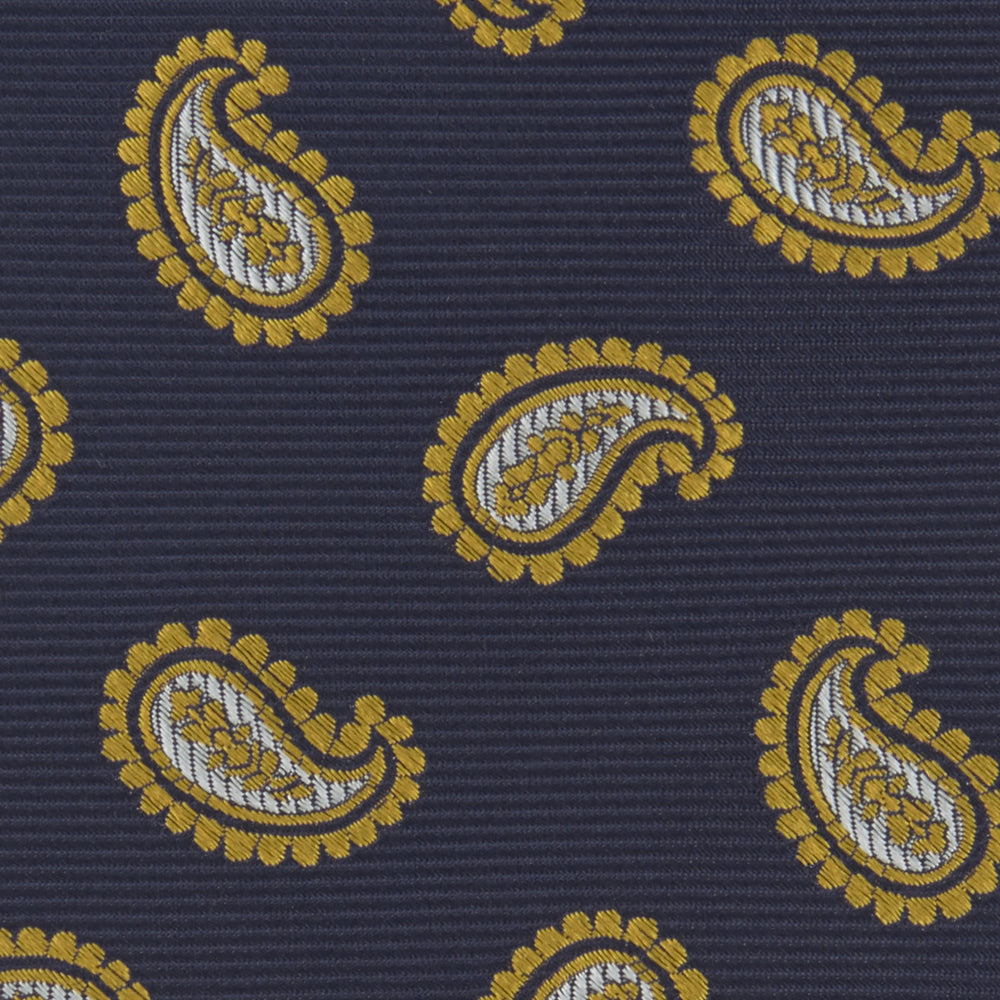 The Turnbull & Asser Navy and Gold Floating Paisley Silk Tie features a repeating yellow and white paisley pattern, shown rolled with the pointed end facing forward against a white background.