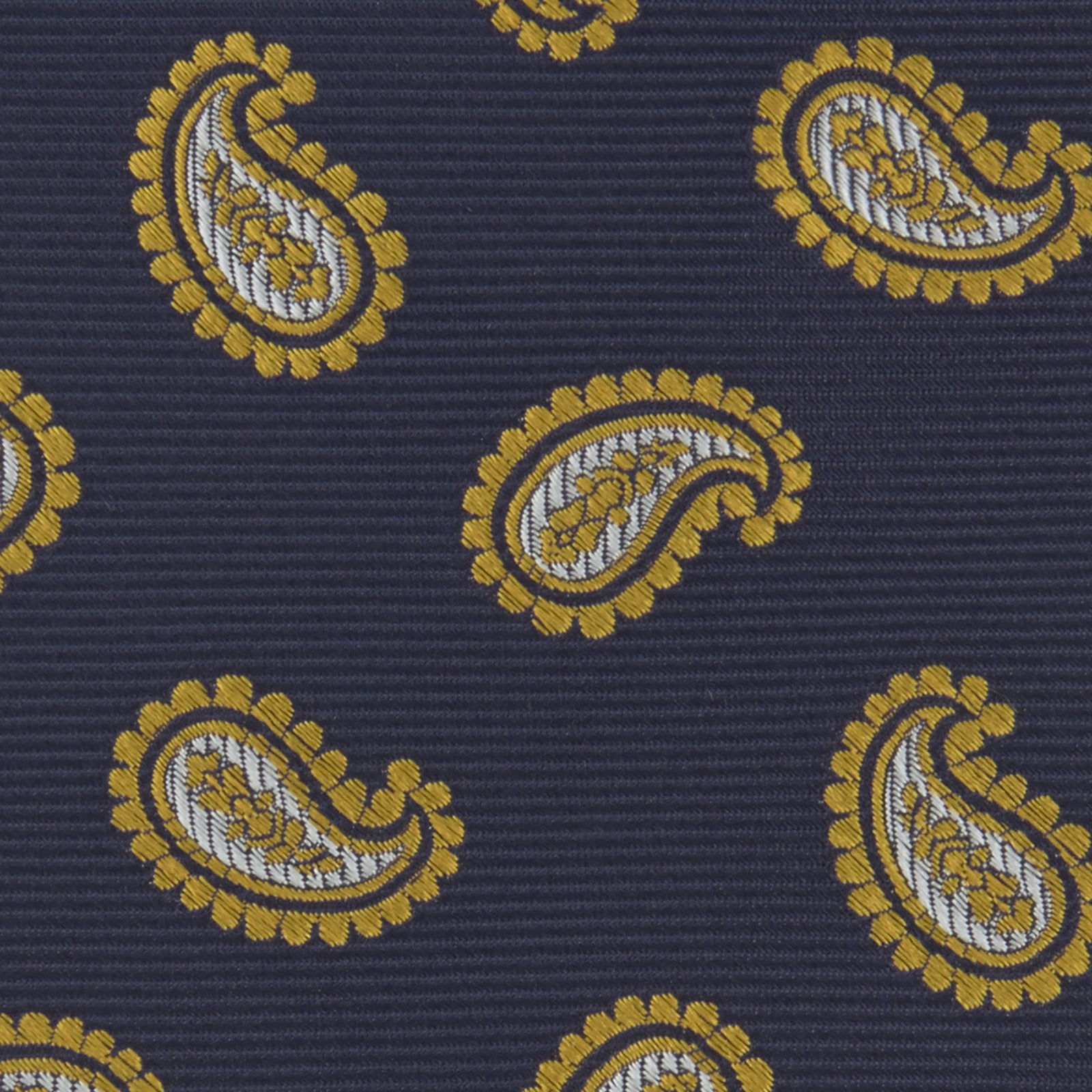 View 3 of product The Turnbull & Asser Navy and Gold Floating Paisley Silk Tie features a repeating yellow and white paisley pattern, shown rolled with the pointed end facing forward against a white background.