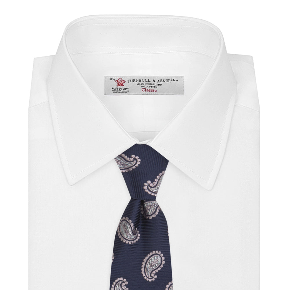 The Turnbull & Asser Navy and Light Pink Floating Paisley Silk Tie features a classic pink and white paisley pattern—a timeless accessory to enhance any wardrobe.