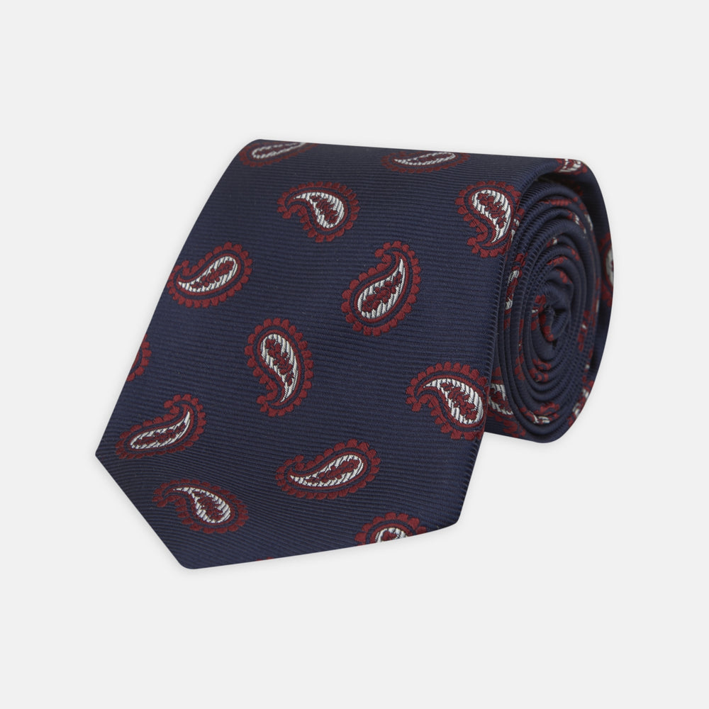 The Turnbull & Asser Navy and Burgundy Floating Paisley Silk Tie is shown rolled up, displaying its repeating paisley design on a plain white background.