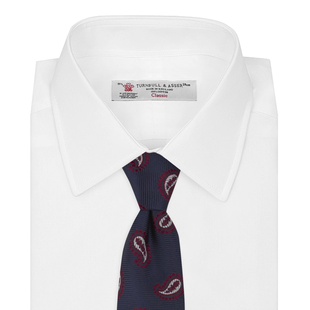 The Turnbull & Asser Navy and Burgundy Floating Paisley Silk Tie is shown rolled up, displaying its repeating paisley design on a plain white background.
