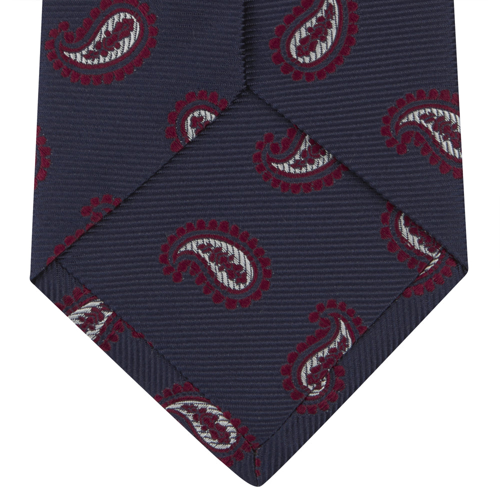 The Turnbull & Asser Navy and Burgundy Floating Paisley Silk Tie is shown rolled up, displaying its repeating paisley design on a plain white background.