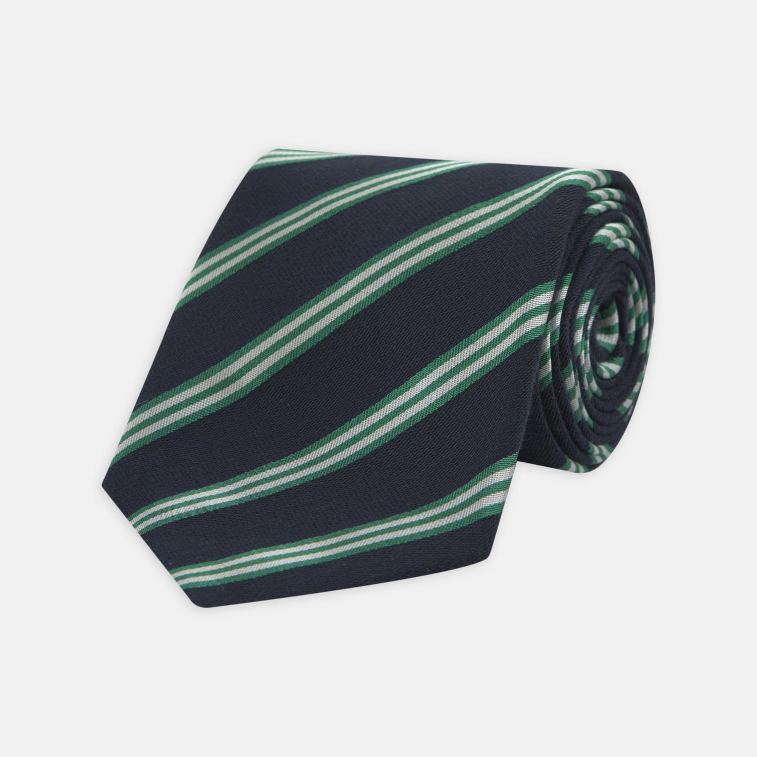 View 1 of product The Turnbull & Asser Navy, Green and White Multi Repp Stripe Silk Tie features elegant diagonal stripes, making it a classic accessory for any occasion. Shown rolled on a white background.