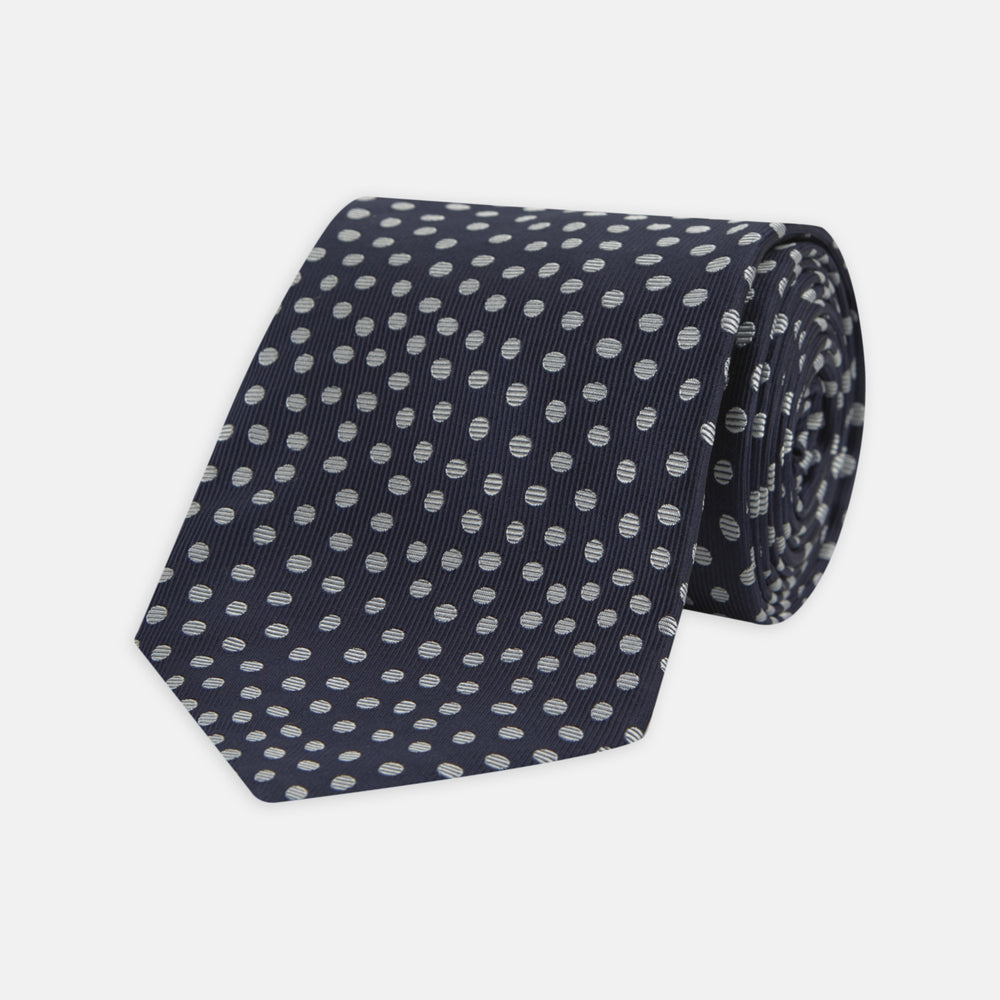 The Turnbull & Asser Navy and White Paint Spot Silk Tie features evenly spaced white spots on classic navy, shown rolled up on a white background—ideal for complementing your favorite office shirt.