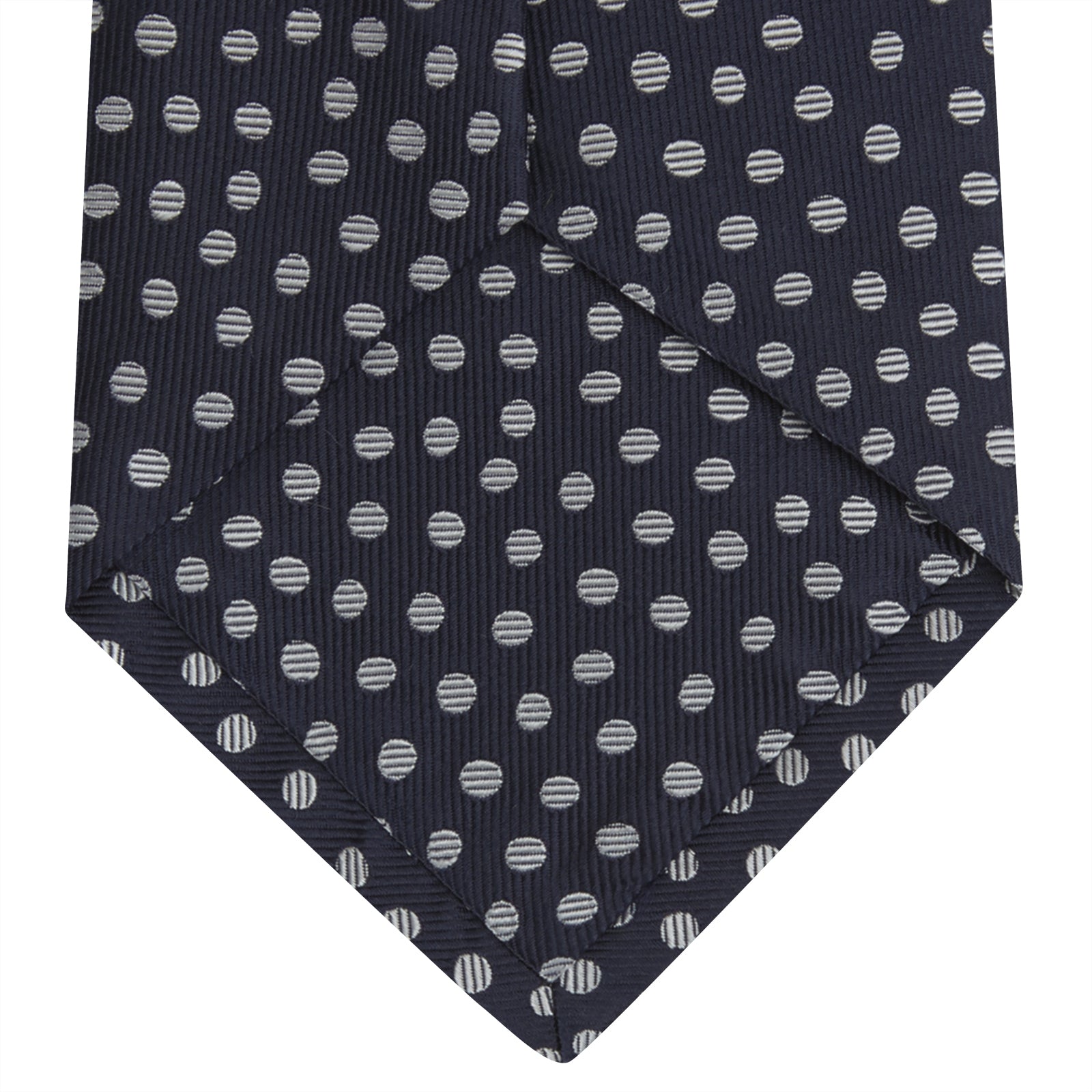 View 4 of product The Turnbull & Asser Navy and White Paint Spot Silk Tie features evenly spaced white spots on classic navy, shown rolled up on a white background—ideal for complementing your favorite office shirt.