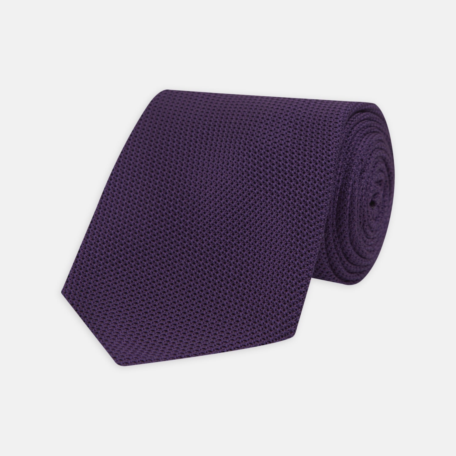 View 1 of product The Turnbull & Asser Plum Grenadine Silk Tie, featuring a textured grenadine weave, is shown rolled up on a plain white background.