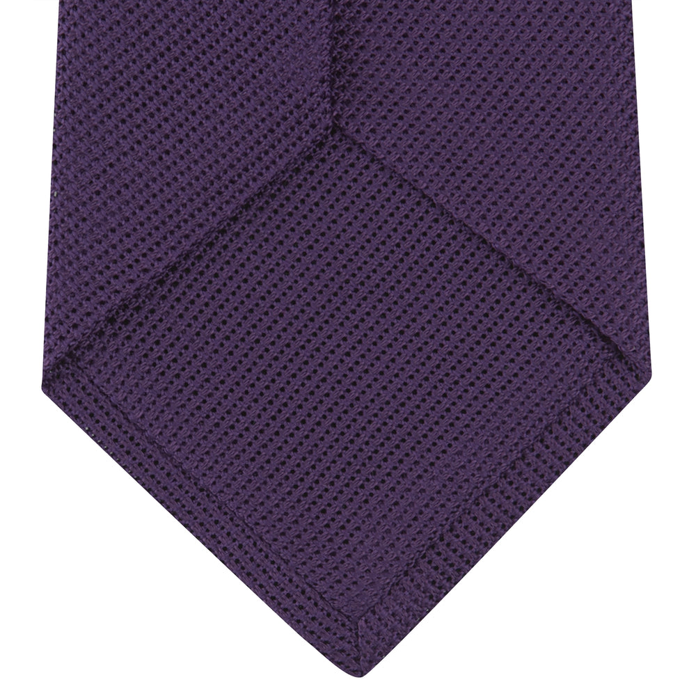 The Turnbull & Asser Plum Grenadine Silk Tie, featuring a textured grenadine weave, is shown rolled up on a plain white background.