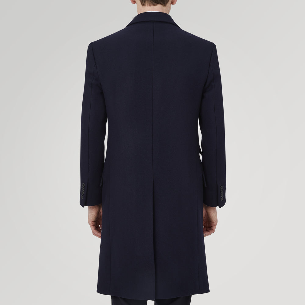 The Turnbull & Asser Navy Lambswool Joseph Overcoat, a men's knee-length coat with notched lapels, a single-breasted front, and three flap pockets per side, is shown against a plain white background.