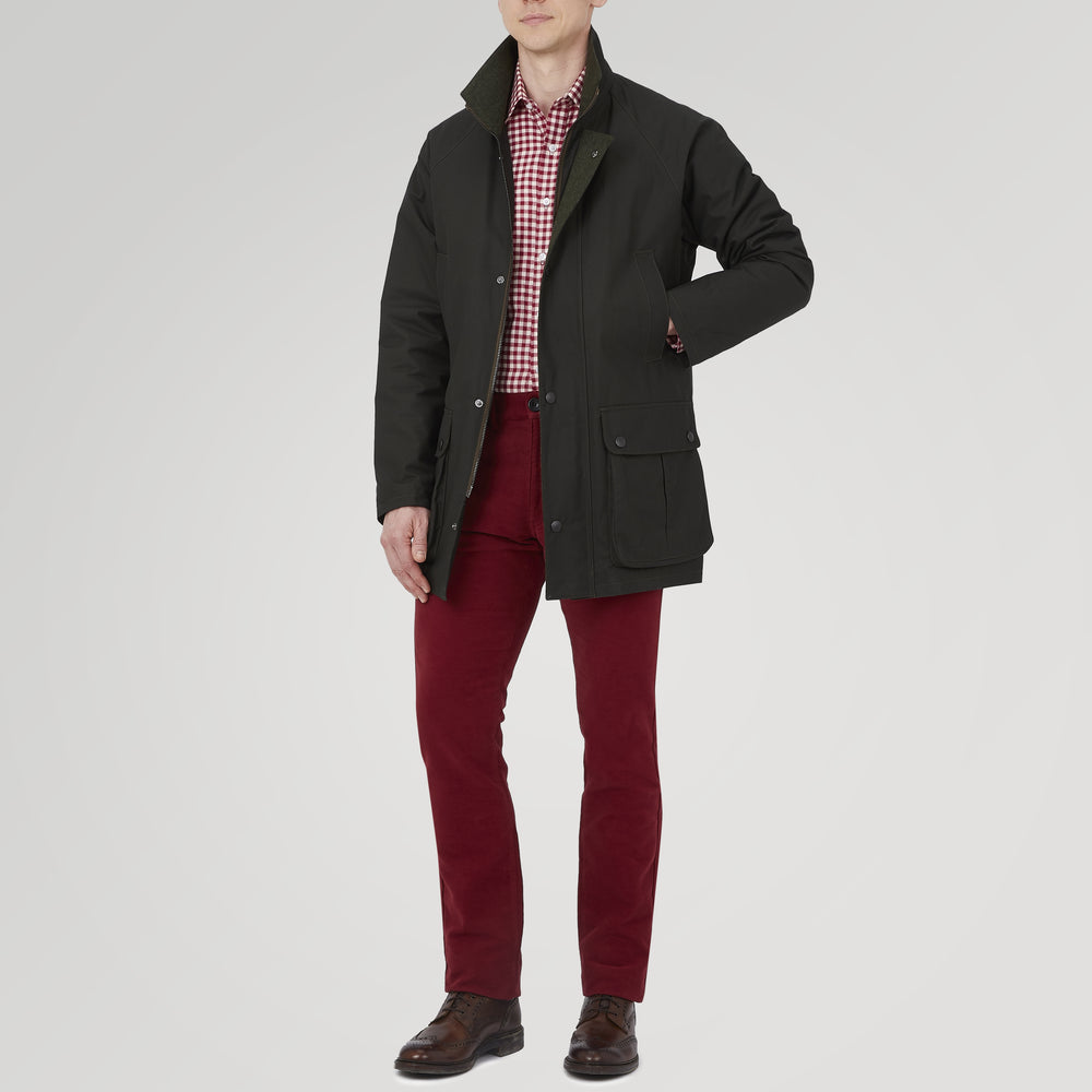 The Turnbull & Asser Dark Green Waxed Cotton Field Coat features a straight fit, button-up front, two large bottom flap pockets, slanted chest pockets, and a contrasting collar. Shown against a plain white background.