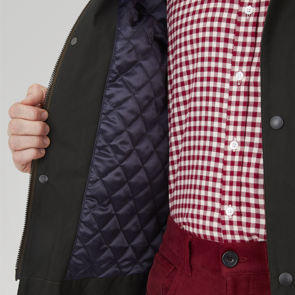 The Turnbull & Asser Dark Green Waxed Cotton Field Coat features a straight fit, button-up front, two large bottom flap pockets, slanted chest pockets, and a contrasting collar. Shown against a plain white background.