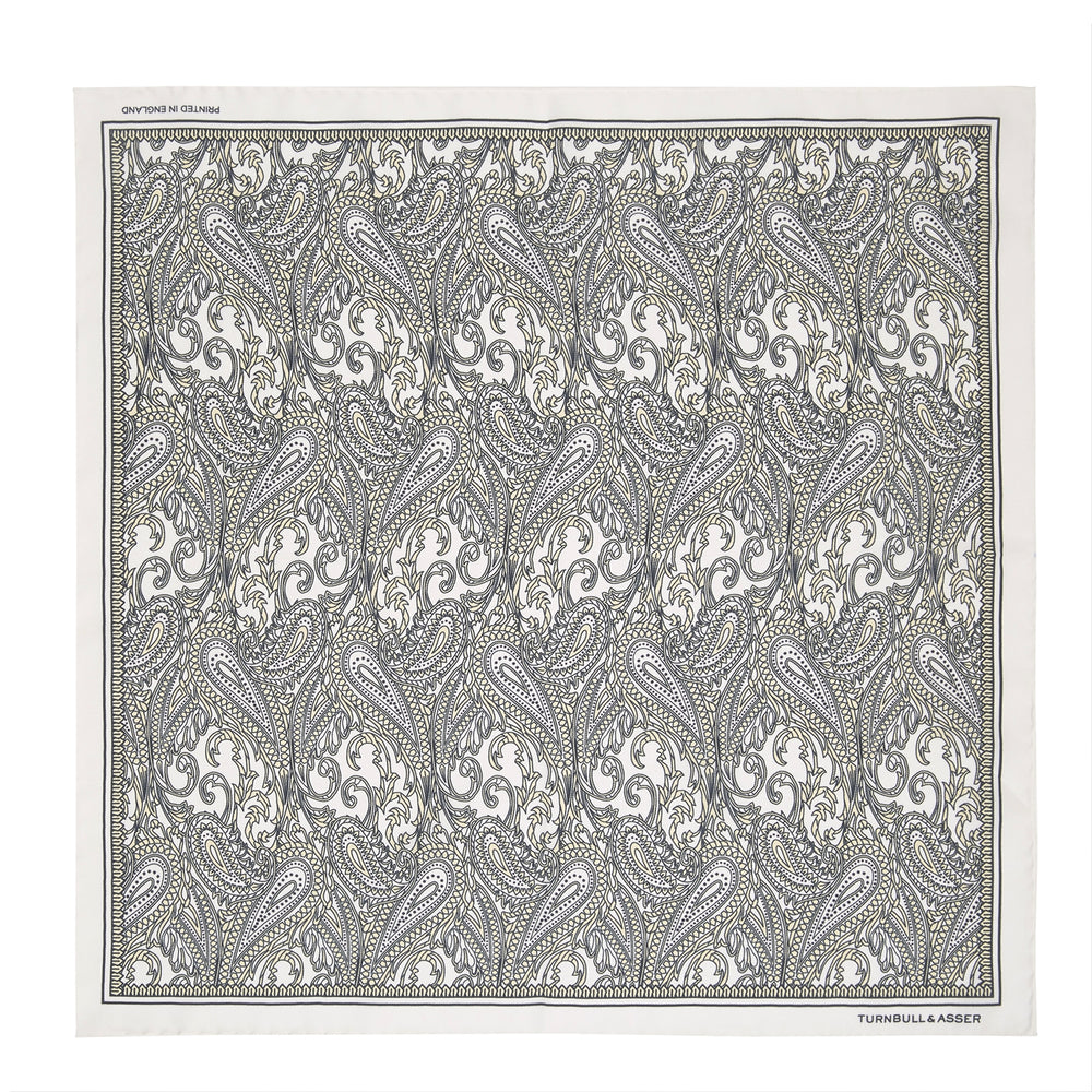 A White and Yellow House Paisley Silk Pocket Square by Turnbull & Asser, featuring an elegant house paisley pattern and the brand name printed in the bottom right corner.